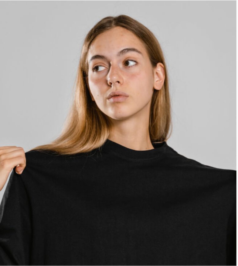 Woman stretching the collar of a black tee to show its knit